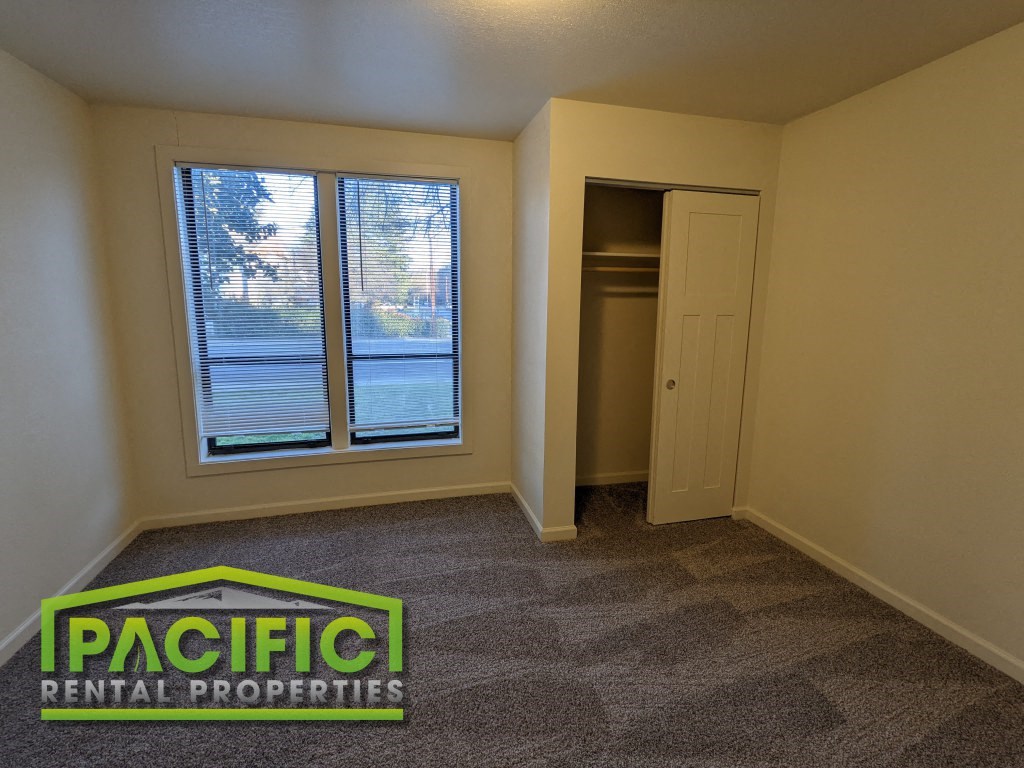 an empty living room with a closet and a window