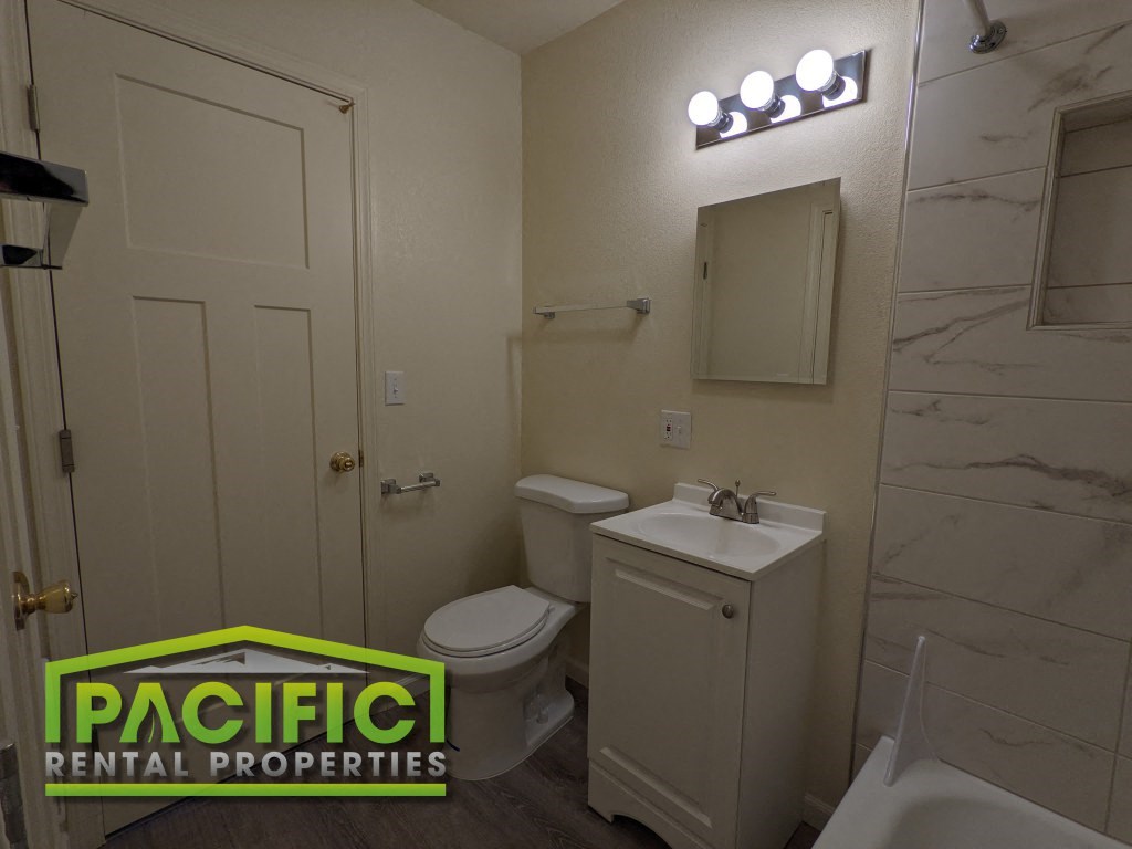a bathroom with a toilet sink and mirror and pacific rental properties