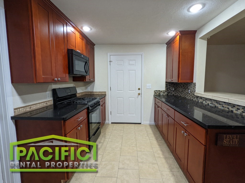 a kitchen with brown cabinets and black counter tops and a white door