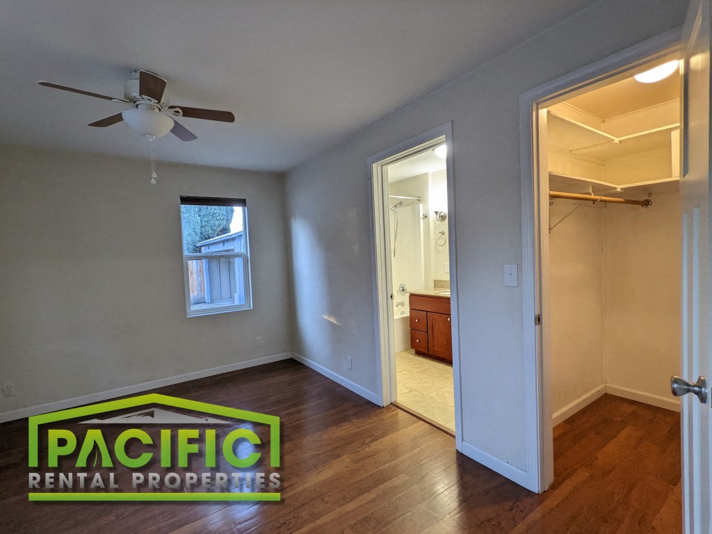 a living room with a ceiling fan and a doorway into a bathroom