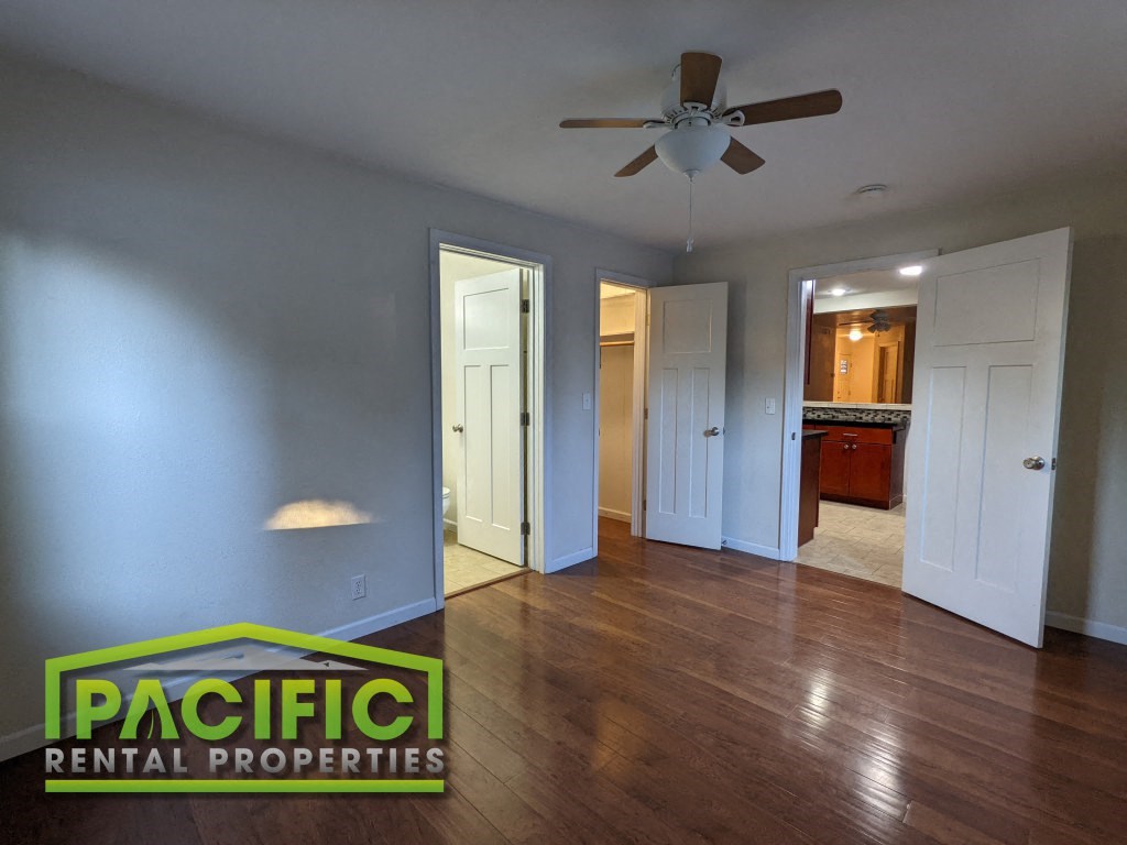 an empty living room with wood floors and a ceiling fan