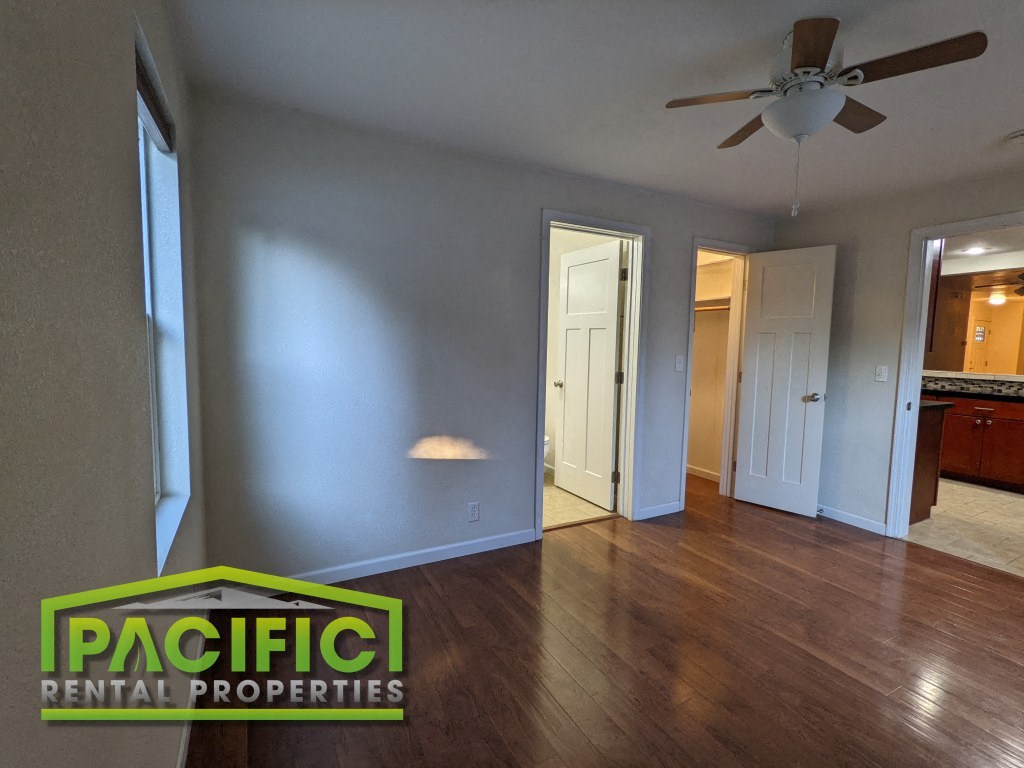 an empty living room with wood floors and a ceiling fan