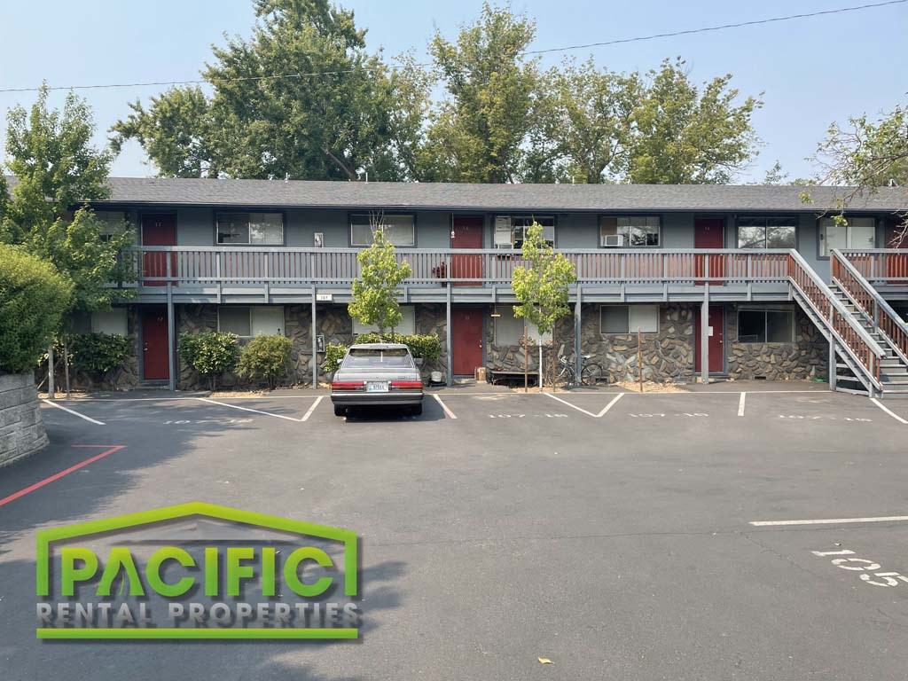 an apartment building with a parking lot and a car parked in front of it