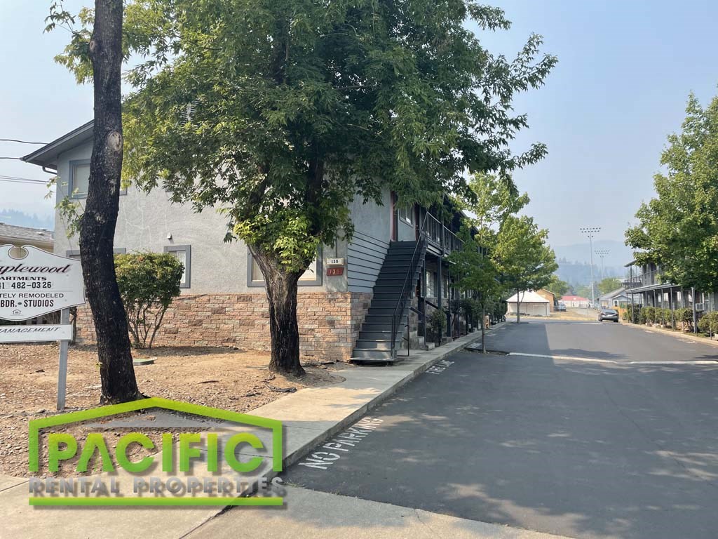 an empty street in front of a building with trees
