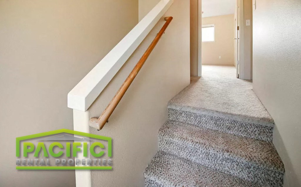a set of stairs with a wooden rail and a white carpeted staircase