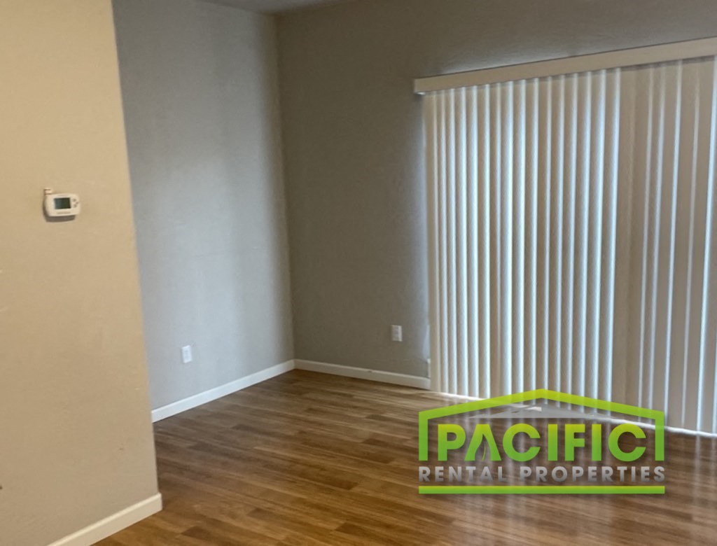 a room with a vertical blinds on the wall and a wooden floor