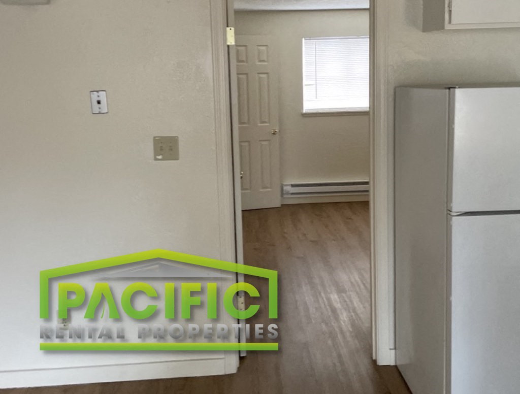 an empty kitchen with a refrigerator and a door