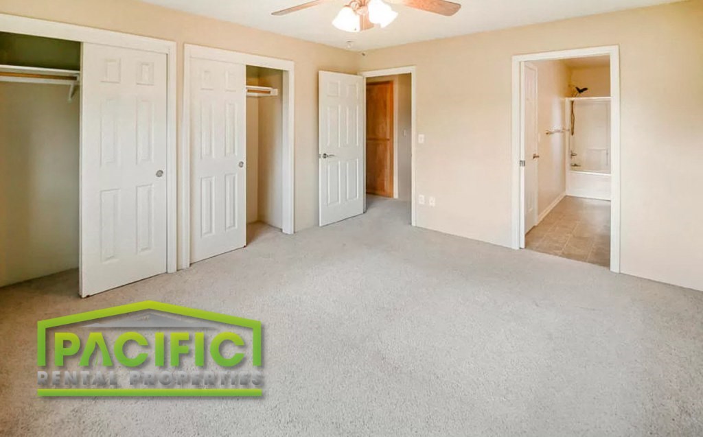 a empty living room with white doors and a ceiling fan