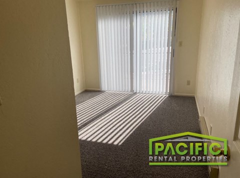 a living room with a window and a carpet and a pacific rental properties logo