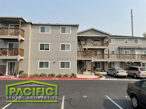 an apartment building with cars parked in a parking lot