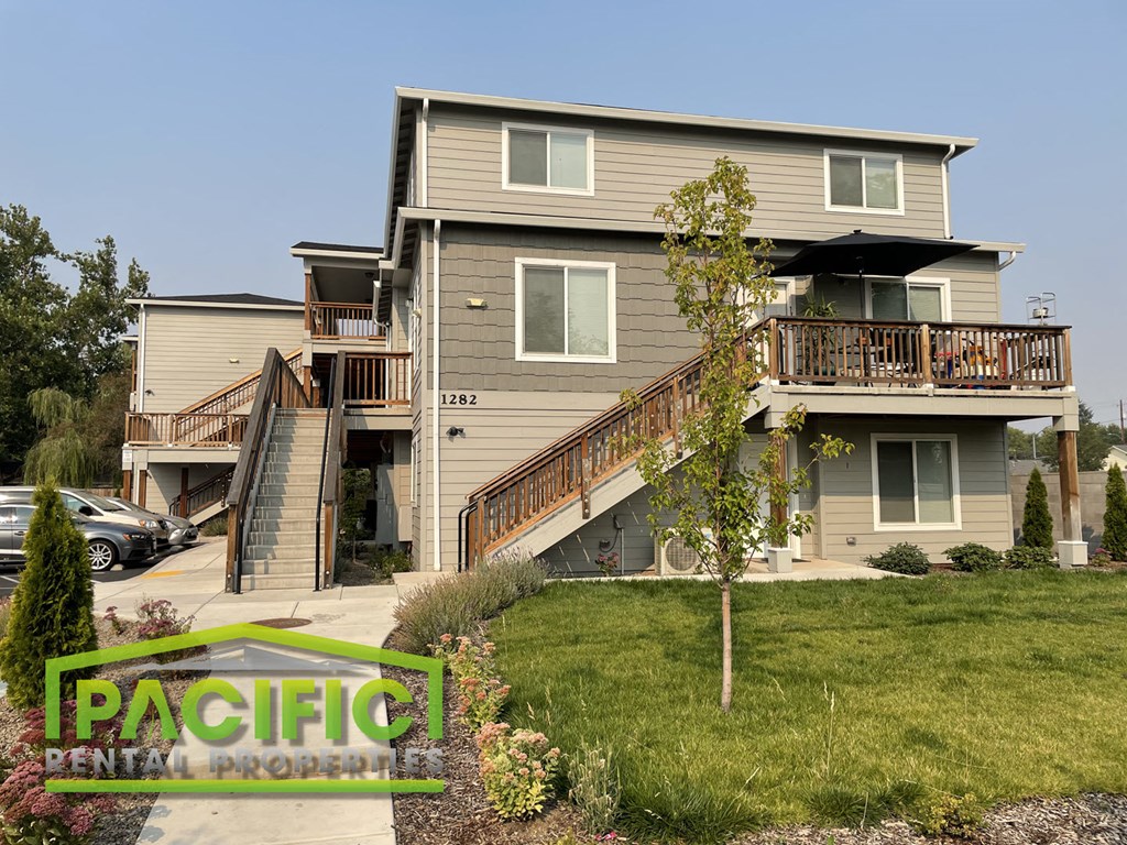 a house with stairs and a yard with a tree