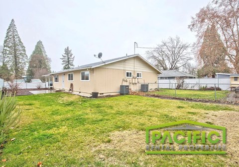 A house with a lawn in front of it and trees in the background.
