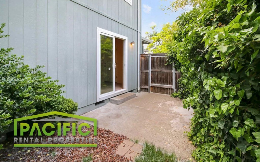 a patio in front of a blue house with a door