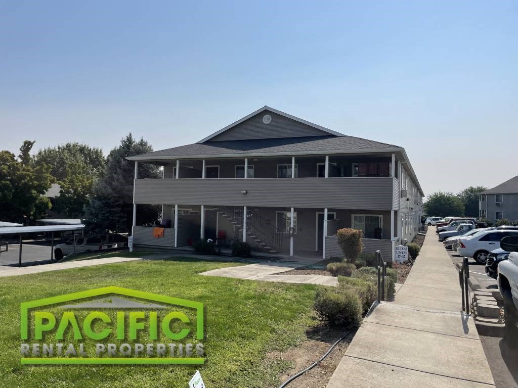 a gray building with a porch and a sidewalk