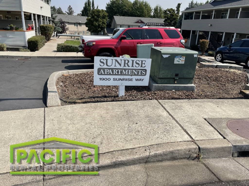 a sign for sunrise apartments on the side of the street
