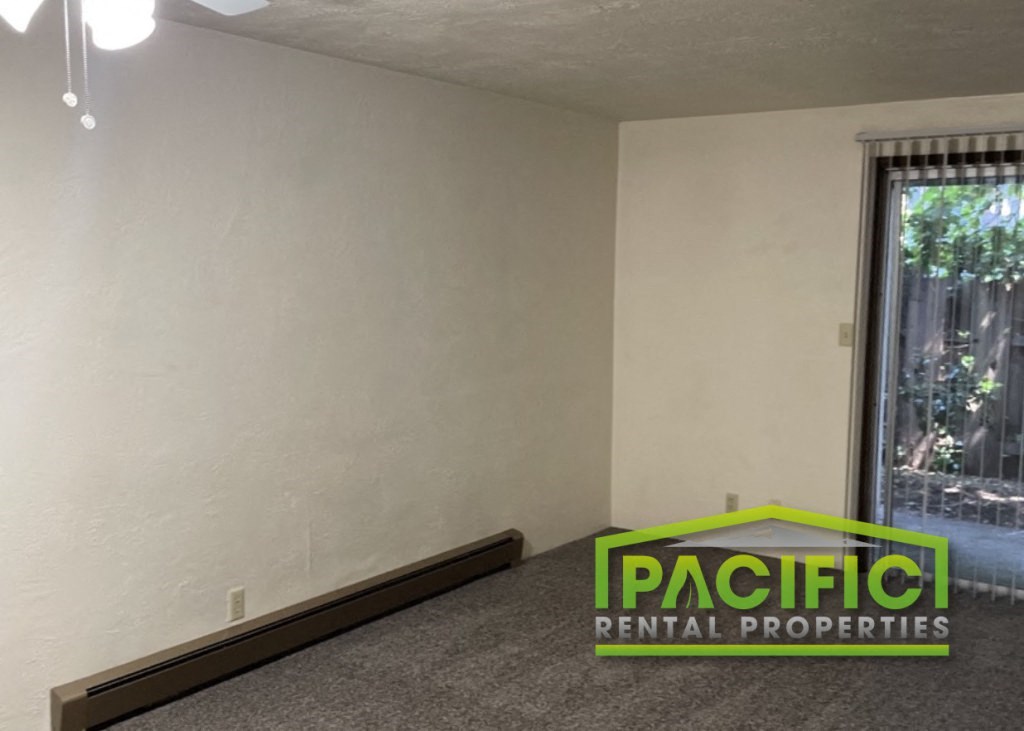 an empty living room with a window and a pacificentalental properties logo on