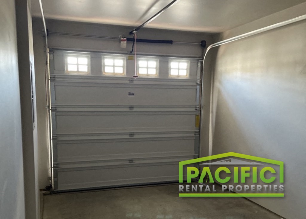 a white garage door in a building with a pacific rental properties logo