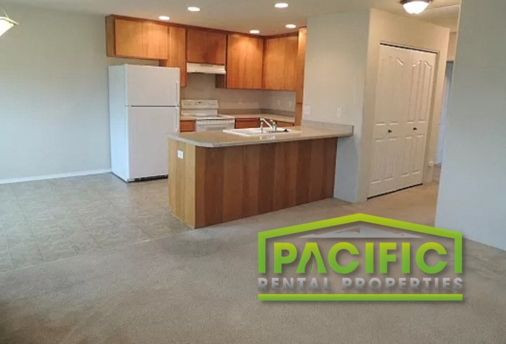 an empty kitchen with a white refrigerator and wooden cabinets