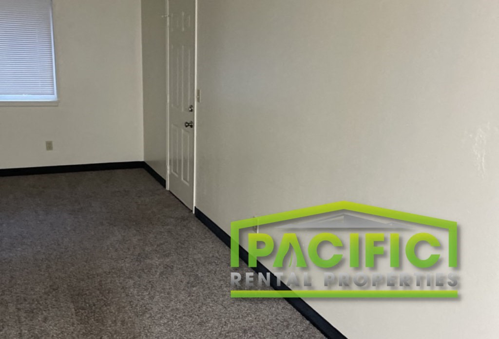 a carpeted room with a door and a green logo on the floor