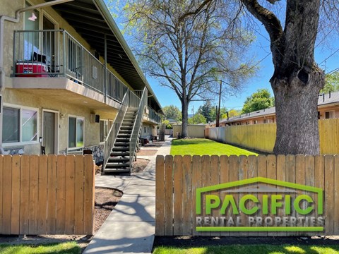 a fence with a pacific rental properties sign in front of a building