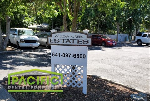 a sign for willow creek estates rates in front of a parking lot