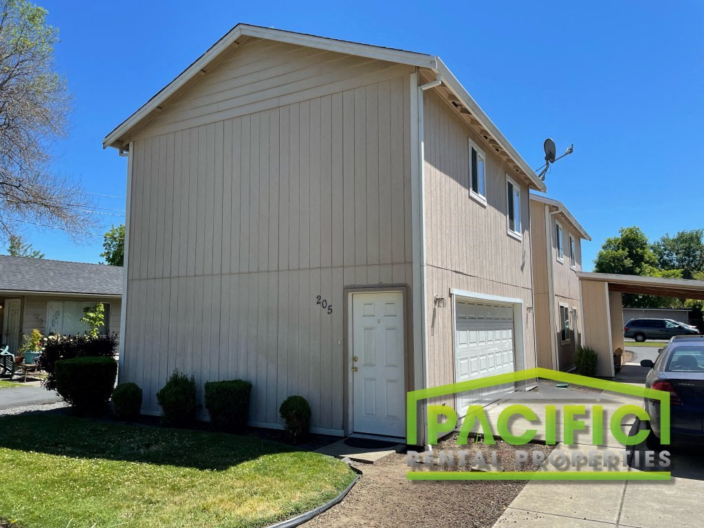 a white building with a white garage and a green yard sign