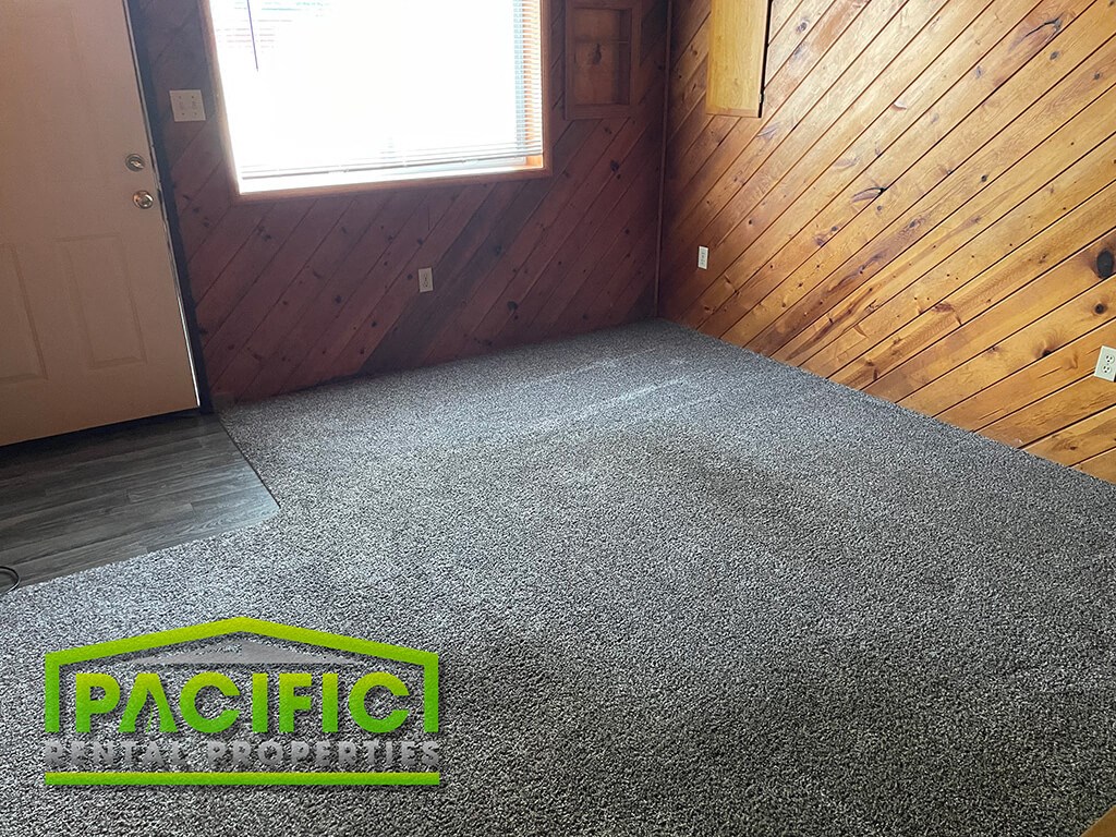 a carpeted room with a door and a carpet logo on the floor