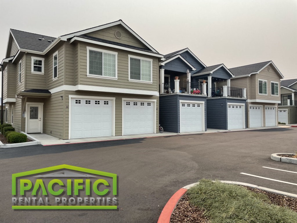 a beige and with garage doors and a parking lot