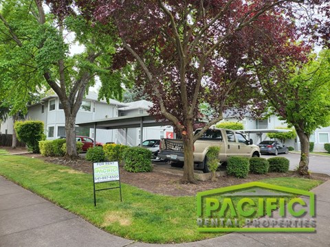 an apartment building with a parking lot and trees