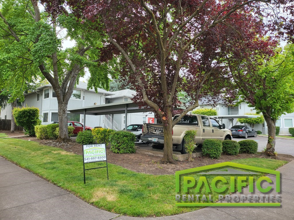 an apartment building with a parking lot and trees