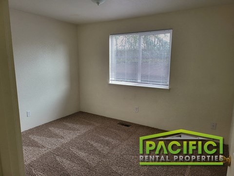 an empty room with a window and a carpeted floor
