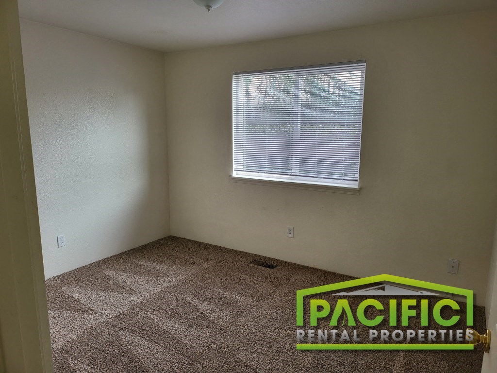 an empty room with a window and a carpeted floor
