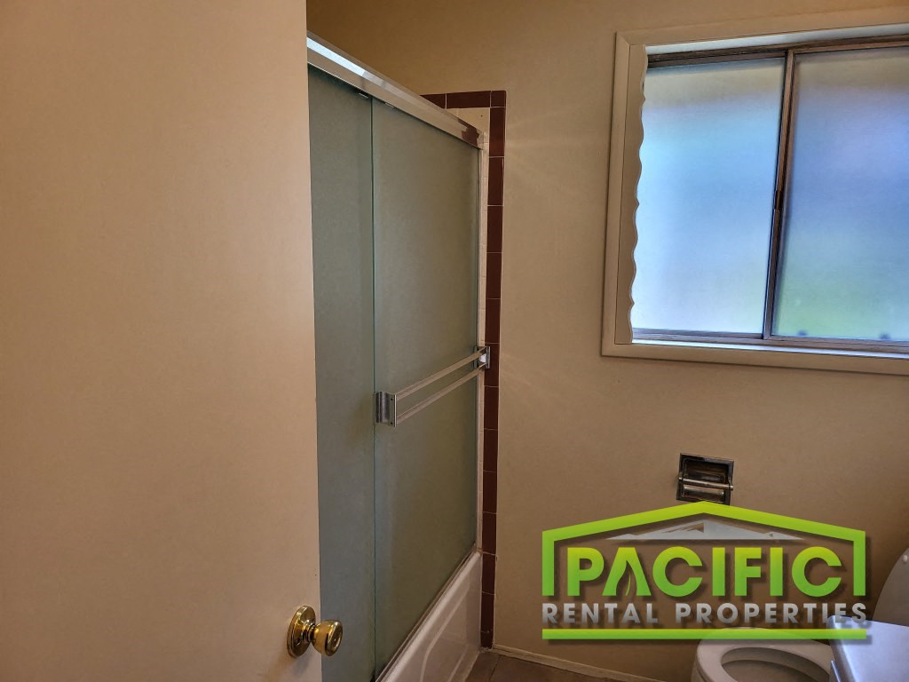 a bathroom with a shower and a toilet and a pacificentalental properties logo