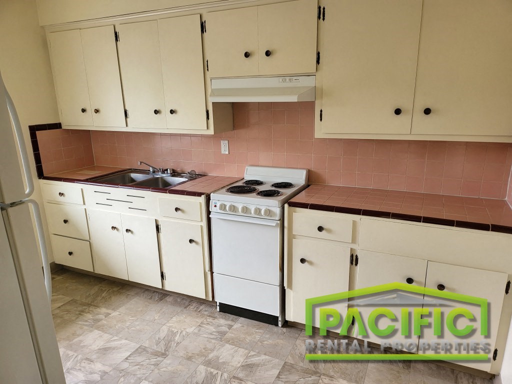 a kitchen with white cabinets and a stove and a sink