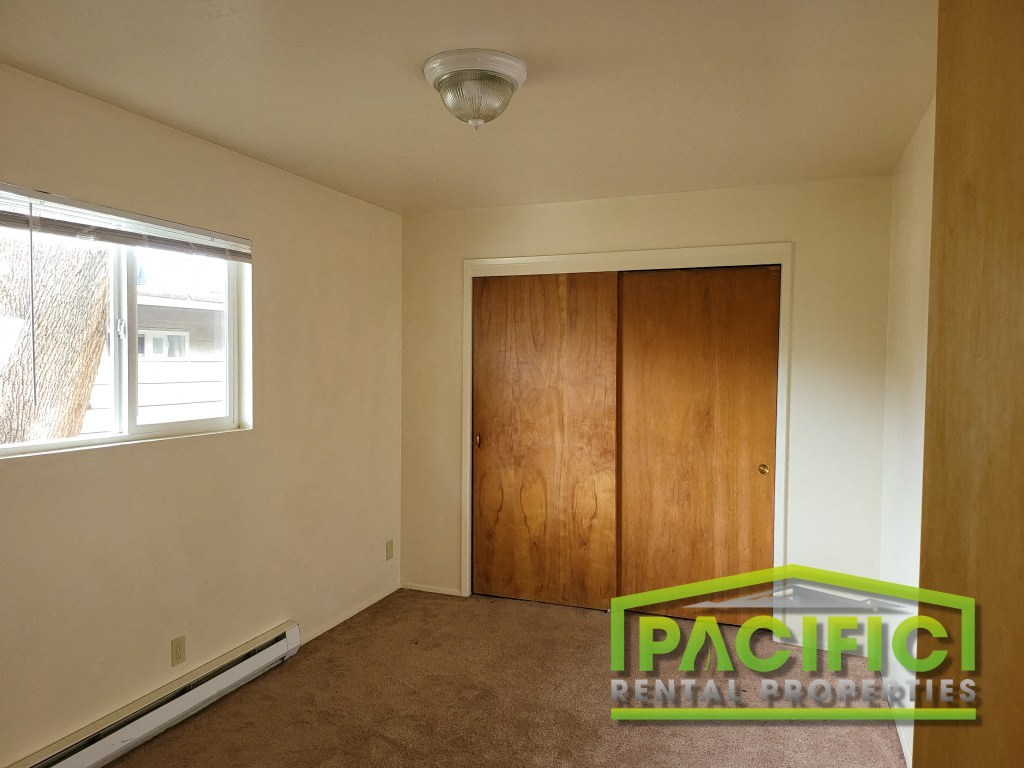 a bedroom with a wardrobe and a window and a carpeted floor