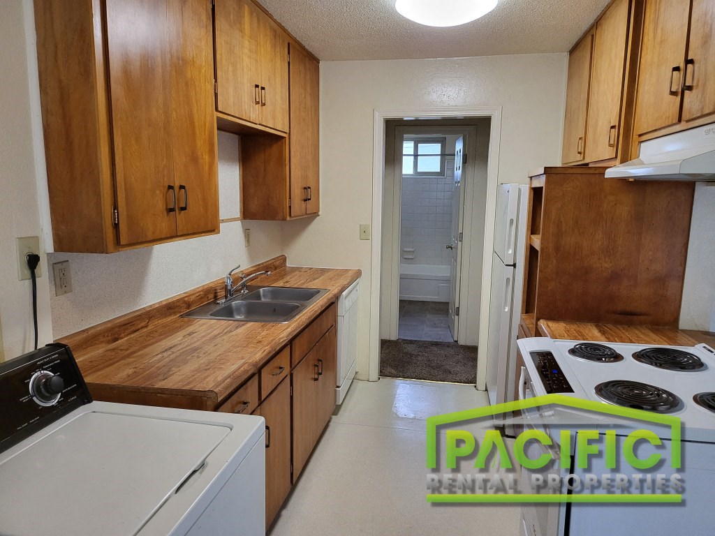 a small kitchen with wooden cabinets and white appliances