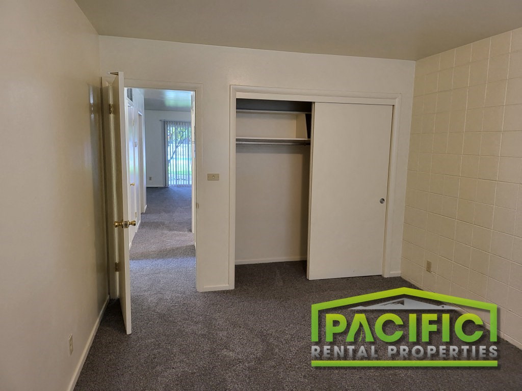 a bedroom with an open closet and a carpeted floor