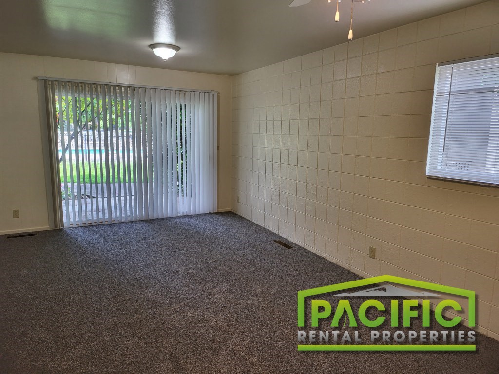 a empty room with a window and a pacific rental properties logo on the floor