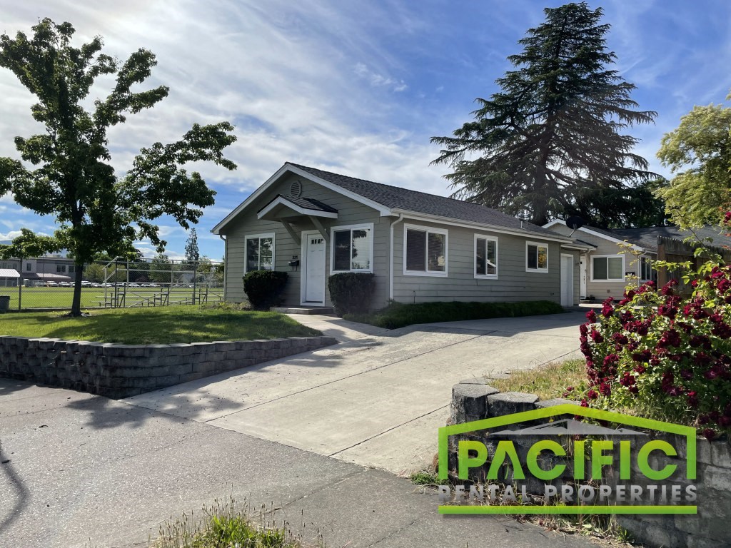 a small gray house with a driveway and a sign that reads pacific northwest properties