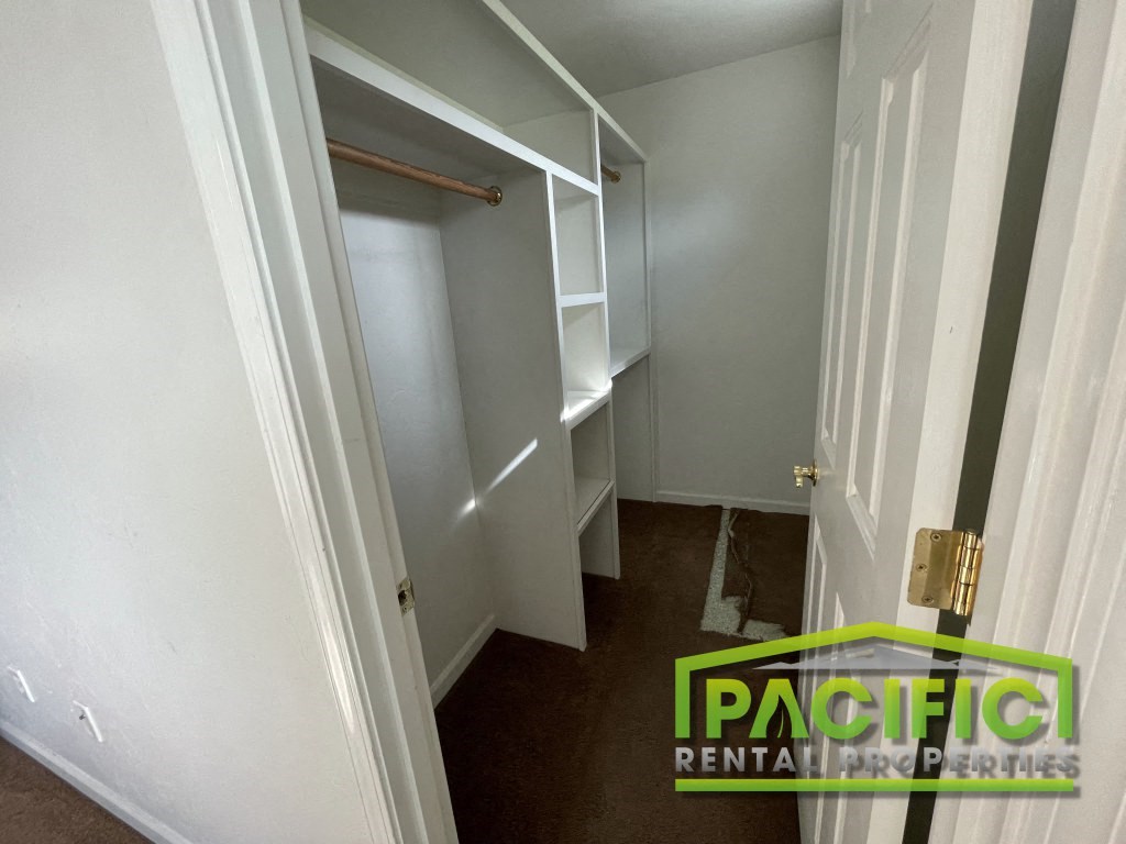 a walk in closet in a small room with a door open