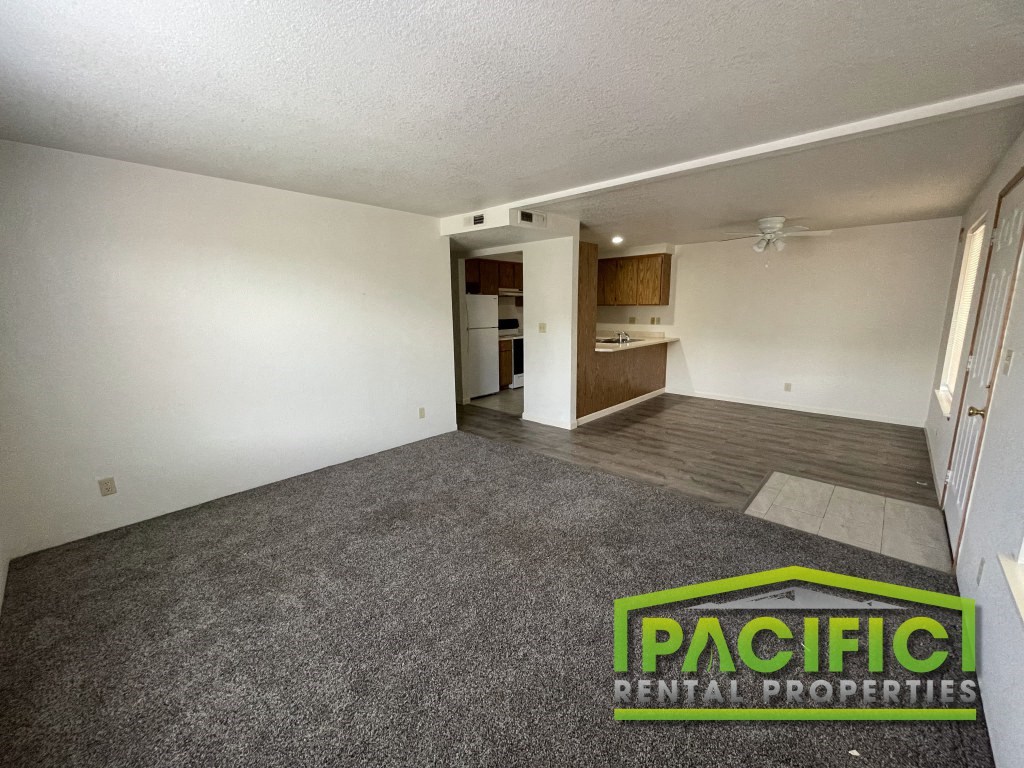 an empty living room with carpet and a kitchen