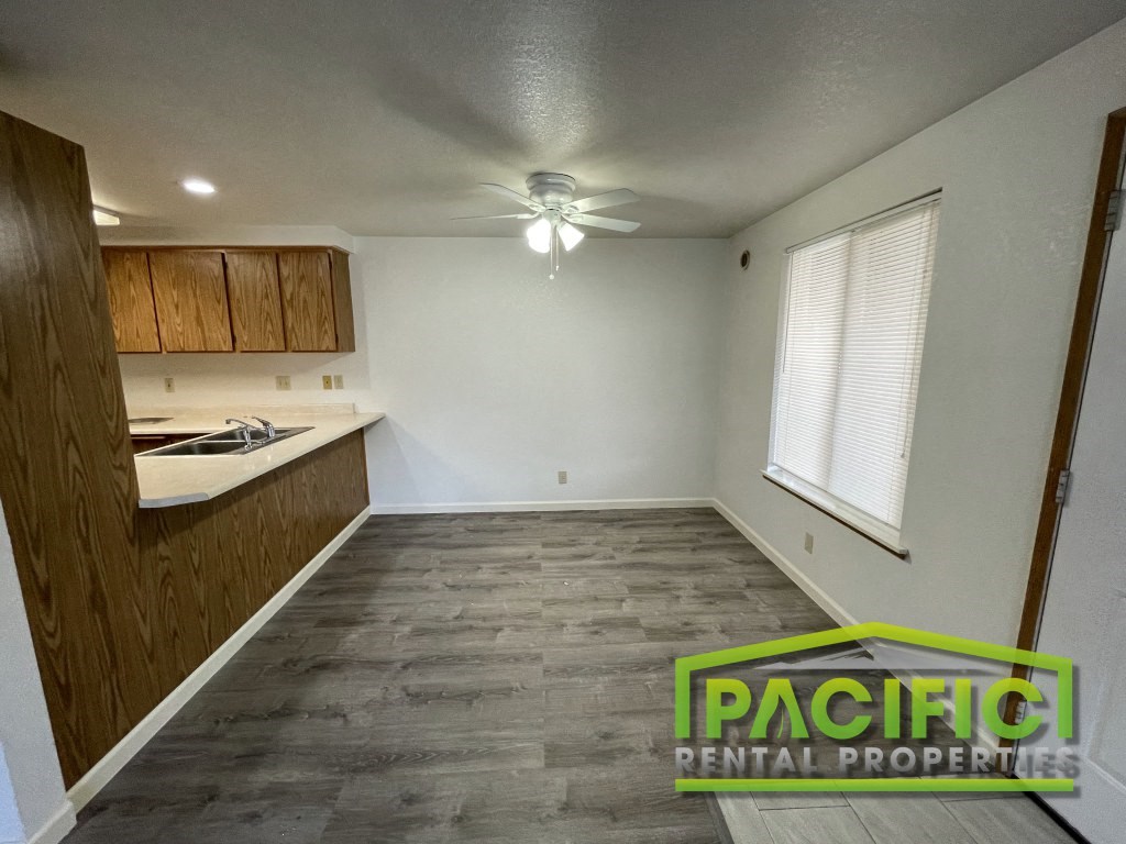an empty kitchen with wood flooring and a ceiling fan