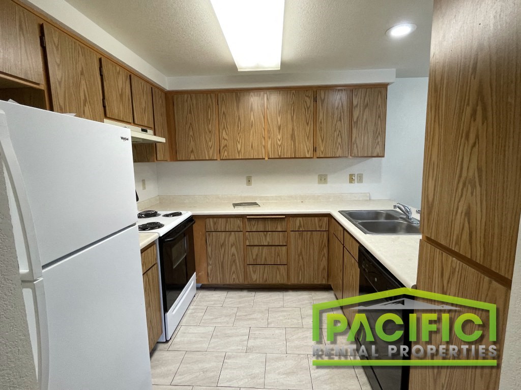 a kitchen with wooden cabinets and white appliances and a refrigerator