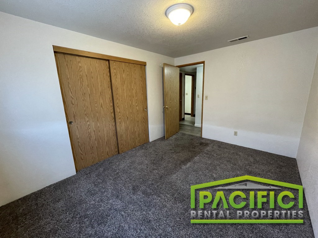 an empty room with a carpeted floor and wooden closet doors