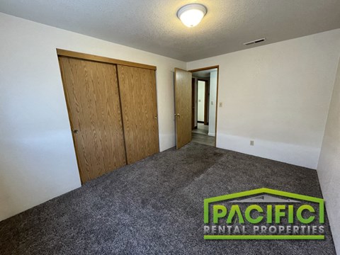 an empty room with a carpeted floor and wooden closet doors