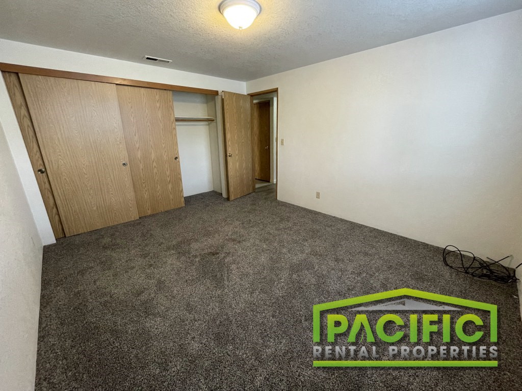 a living room with carpet and a door to a closet