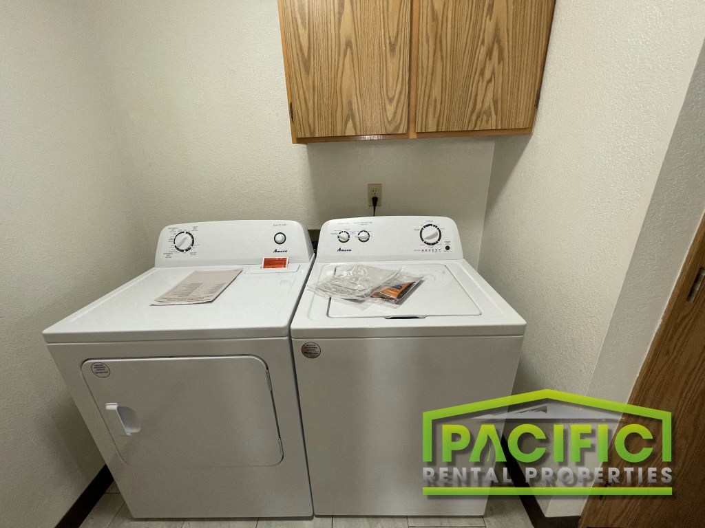 a washer and dryer in a room with a cabinet and a washing machine