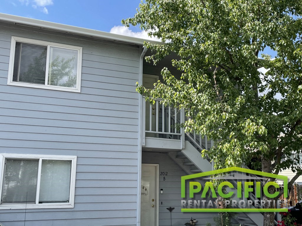 a house with a pacific rental properties sign in front of it