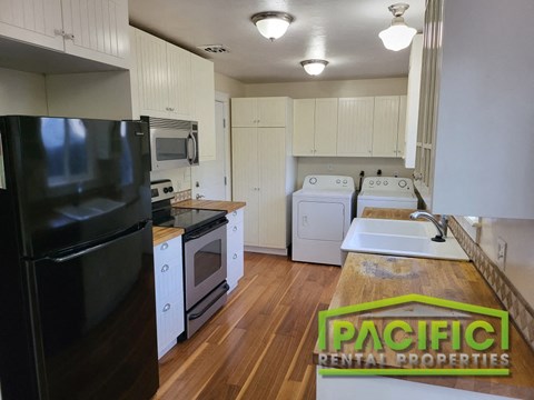 a kitchen with white cabinets and appliances and a black refrigerator