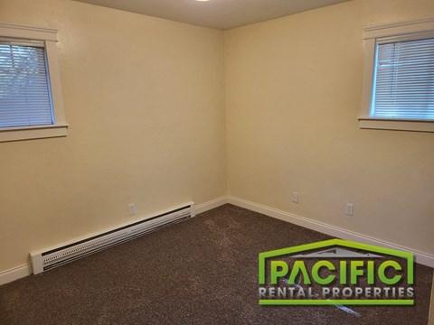 an empty room with a pacific rental properties logo on the floor